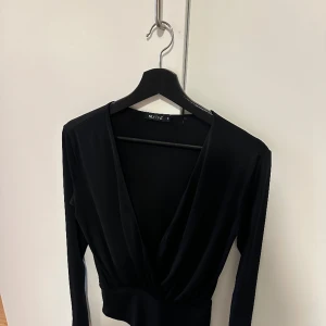 Urringad body  - Urringad body i storlek S från NLY ONE, silk-liknande material. Svart. 