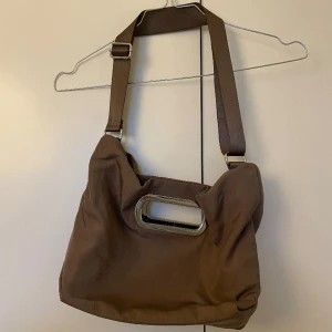 Brun väska från weekday.  - Brun väska från weekday i bra storlek med ett innerfack och silvriga detaljer. 