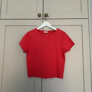 Croppad t-shirt  - Croppad, korallfärgad t-shirt från Gina Tricot som passar perfekt till sommaren!! Se sista bilden för att se färgen bättre i verkligheten. Storlek XL, men passar allt från storlek XS-XL, beroende på hur löst man vill att den sitter.💕