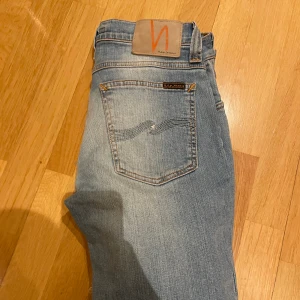 Nudie jeans - Ett år ljusblåa nudie jeans med de eftertraktade och snygga slitningar som är perfekt inför sommaren. Priset är inte hugget i sten så hör av er vid några funderingar eller prisförslag😊