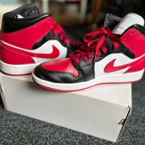 Air Jordan 1 Mid - Snygga Air Jordans 1 Black/Gym Red-White. Köpte för något år sedan men inte riktigt användit dem men nu har de blivit för små🙁. Storlek 42, Priset är förhandlingsbart