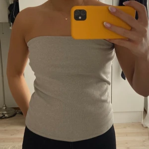 Grå beige glittrig bandeau topp - Gillar denna jätte mycket den är bara en aning för stor därav säljer jag! Aldrig använt, från Stockholm studio. Den har som en gummi kant så att den inte ska åka ner när man har på sig den💗