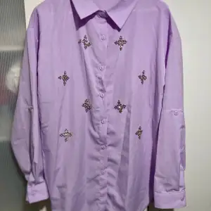 Ny skjorta/blus i strl XL med diamanter/rhinestones/pärlor på. Skjortan är helt ny, aldrig använd. Material: 100% polyester 