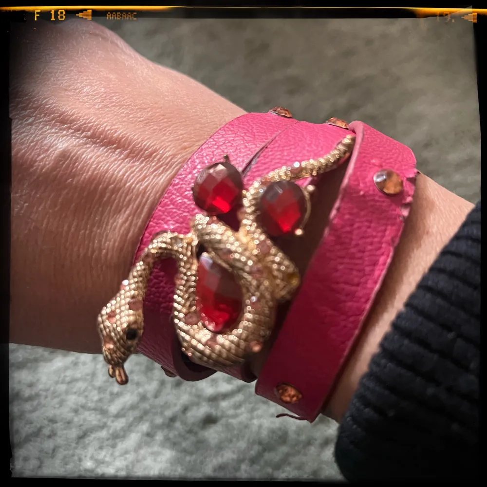 Rosa armband i skinnimmitation med orm i guld och rosa stenar. Välanvänt, så lite slitage, se bild. 55 cm x 1,2 cm. Accessoarer.