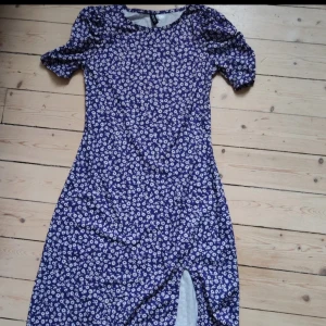 Mjuk lila midiklänning med vita blommor  - Jättebekväm klänning från HM med ryschade ärmar och en slits. 