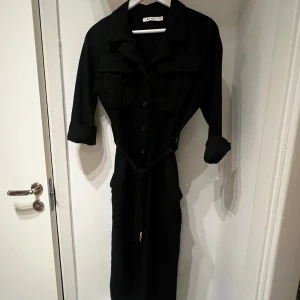 Jumpsuit  - Svart jumpsuit från NA-KD med fickor uppe och nere Benen är något korta i modellen  Samma modell som den beiga på bild 3