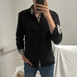 Svart burberry skjorta - Säljer nu min fräscha burberry skjorta som är knappt använd. Skjortan är i M och modellen på bilden är 181 cm.
