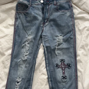 Snygga Y2K jeans med kors - Säljer pga att dem är för små för mig! Finns inget midjemått men tolkas som  S/M! Jätte fina på och trendiga!💕✨🌹Kan diskutera pris!!!!😚😚