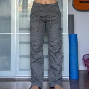Grå Cargopants - Grå cargopants som har snören vid midjan och vid fotlederna. Innerbenslängd: 78cm; Ytterbenslängd: 104cm; Midjemått: 81 cm (kan knytas åt). Jag är 166cm.