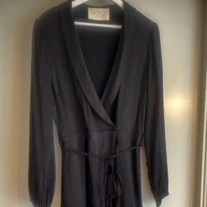 Klänning från Notes Du Nord - Knappt använd jättefin klänning med tungt härligt fall. Omlott med knappar och skärp. Ärmarna har elastiska band så man kan dra upp dem om man vill. Osymmetriskt fall så lite längre bak. Svårt att ta rättvisa bilder men hör av dig om du vill. 