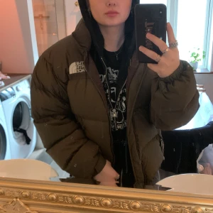 The North Face jacka - The North Face retro Nuptse dunjacka. Den är en brun färg med en liten nyans av grön. Har haft i kanske 2 år och använt max 5 gånger. Den är i mycket fint skick inga hål eller slitningar och fluffig och fin i dunet. Nypris 3895kr på zalando🫶🏻