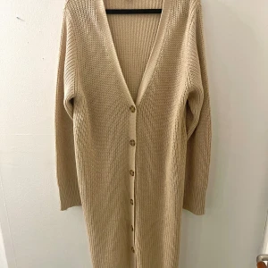 LÅNG STICKAD KOFTA MED KNAPPAR - Lång stickad kofta med bruna knappar, perfekta tillskottet till garderoben.  Strl. XL normal i storleken kan gränsa till lite mindre. Aldrig använd endast testad! Den är gjord av 60% bomull, 40% akry. Tvättas i 30 grader och kan inte torktumlas.