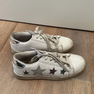 Stjärn skor - Ett par sneakers med stjärnor i olika färger, och silver där bak. Ganska annvända men man kan putsa till det vita på skon! Storlek 38 men passar även 39.⭐️