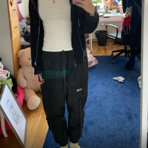 Bershka Cargo Pants - Svarta byxor med 12 fickor i olika storlekar, Byxstorlek dam Medium. Lite korta i benen, jag är ca 179cm och benen på dessa är lite korta för mig. 70% bomull 30% polyester, ganska hårt material, slitstark, håller bra! 