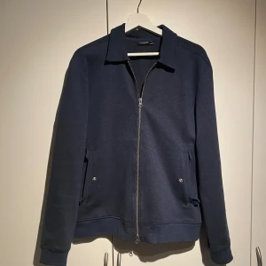 J. Lindeberg overshirt i marinblå - Hej, säljer en overshirt från J.Lindeberg i marinblå färg. Dubbelzip och fickor på sidan. Inte nyskick men sparsamt använd. Nypris 2200kr. Storlek Medium. Snygg passform. Skriv privat för mer info och bilder. Priset är inte hugget i sten. 