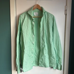 Mintgrön skjorta från Oscar Jacobson - Fräsch mintgrön skjorta från Oscar Jacobson i bomull. Slim fit-modell med klassisk/cutaway krage och vita knappar framtill. Långärmad och stilren design som ger en clean look. Perfekt för dig som gillar färg och vill sticka ut lite extra.