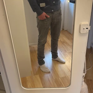Gråa replay jeans - Säljer ett par grå jeans från replay. Jeansen har en snygg tvättad look och raka ben med normal midja. Perfekt för dig som gillar stilrena och enkla jeans med modern känsla. Jeansen är använda och det ser man men inte så tydligt.  Replay loggan högst upp på jeansen där bak är inte i perfekt skick men man märker knappt eftersom ens tröja täcker det.