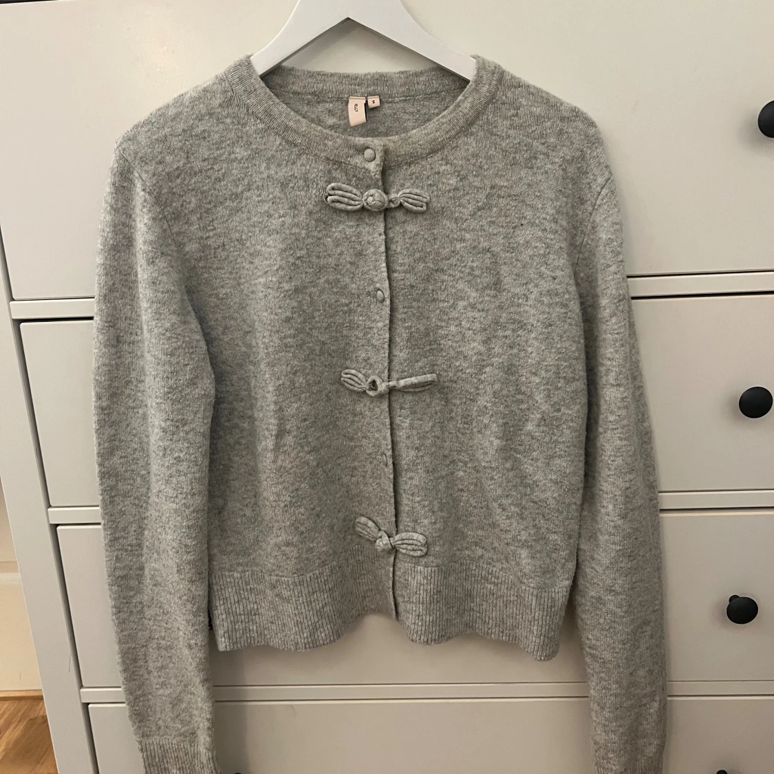 Grå kofta med rosettknäppning