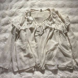 Vit blus med volanger från H&M - Vit blus från hm med volanger i nytt skick perfekt för sommaren och varma dagar går att styla med jeansshorts. Storlek s men känns som m