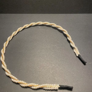 Diadem med pärlor i tvinnad design - Snyggt diadem med tvinnad look, dekorerat med små vita pärlor som ger en elegant och trendig vibe. Perfekt accessoar för att lyfta din frisyr och ge en extra touch till din outfit. Diademet har svarta ändar för bekväm passform.
