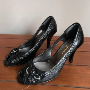 Svarta klackskor med detaljer  - Snygga svarta klackskor från Stefano med glansig finish och öppen tå. Storlek 38 med 8,5 cm hög klack💕