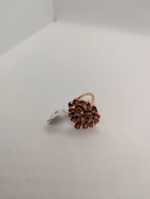 Branble Garnet Ring 19 med röda stenar - Statementring från Branble i storlek 19 med massor av gnistrande röda stenar i blomliknande kluster. Ringen har en varm guldig bas och de röda stenarna ger en lyxig och unik känsla. Perfekt för dig som vill sticka ut med accessoarer.