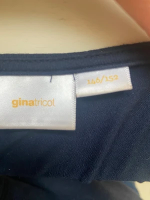 Mörkblå långärmad topp med spets Gina Tricot - Mörkblå långärmad topp från Gina Tricot med snygg v-ringning och spetsdetalj längs halsen. Toppen har en slim passform och är perfekt att styla med jeans eller kjol. Materialet känns mjukt och följsamt mot huden.