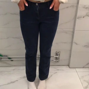 Mörkblå jeans från Armani - Snygga mörkblå jeans från Armani med klassisk rak passform och hög midja. Jeansen har fem fickor och silverfärgad Armani-logga på bakfickan. Tillverkade i slitstarkt denimmaterial som sitter bekvämt och ger en clean look.