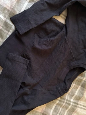 Svart långärmad tröja M/L - Svart långärmad tröja med strukturerad yta och rund hals. Tillverkad i Italien och har en ribbad kant vid halsen. Materialet känns mjukt och har en diskret textur som ger en cool look. Perfekt för lager-på-lager och passar till många olika stilar.