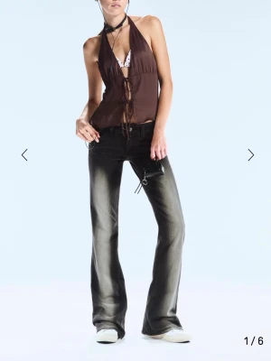 Svarta bootcut jeans med tryck - Säljer ett par svarta bootcut jeans från Cheap Monday med coolt rosa tryck på bakfickan. Jeansen har låg midja och klassisk femficksdesign. Materialet är jeans med en lätt tvättad look och de har en relaxed, loose passform.