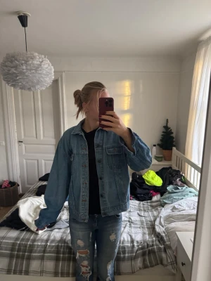 Klassisk blå jeansjacka i storlek C48 - Säljer en klassisk blå jeansjacka i rak modell med knappar framtill och två bröstfickor. Jackan har en avslappnad passform och är tillverkad i slitstarkt jeanstyg. Perfekt att slänga över en hoodie eller t-shirt för en chill look.
