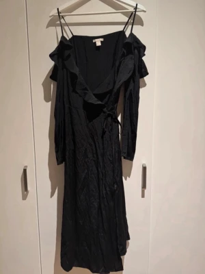 Svart midiklänning - Bara axlar, med ärmar. Omlottknytning. Prickig i tyget.
