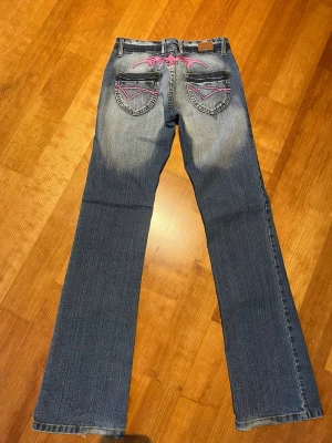 Crazy Age bootcut jeans - Säljer ett par snygga jeans från Crazy Age med rosa broderi. Byxorna är låg midjade och bootcut. Lite slitna längst ner (se sista bilden) 🫶