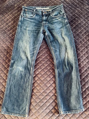 Wrangler jeans blå W30 L34 - Snygga blå jeans från Wrangler i modellen Tony, med klassisk femficksdesign och coola kontrastsömmar på bakfickorna. Jeansen har rak passform och är tillverkade i slitstarkt bomullsmaterial. Perfekt för dig som gillar en tidlös och avslappnad stil.