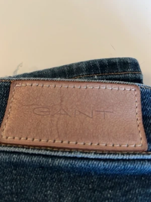 Blå jeans från GANT med rak passform - Snygga blå jeans från GANT med klassisk femficksdesign och läderpatch bak i midjan. Jeansen har rak passform och normal midja, tillverkade i slitstarkt bomullsmaterial. Perfekta för dig som gillar en tidlös och clean look.