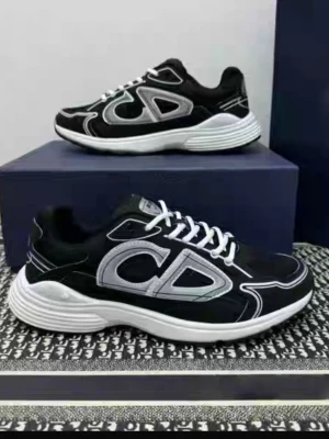 Svarta sneakers med CD-detalj - Säljer ett par svarta sneakers med stora silvriga CD-detaljer på sidan och vita snören. Skorna har en chunky vit sula och coola kontrastsömmar. Perfekta för dig som gillar streetstyle och vill sticka ut lite extra.