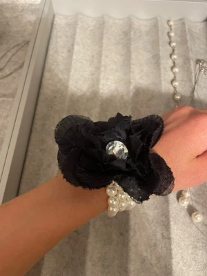 Pärlarmband - Ett fint vitt pärlarmband med en svart blomma på. 
