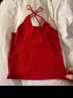 Röd ribbad linnetopp från Zara - Säljer en snygg röd linnetopp från Zara i storlek M. Toppen har ribbad struktur och smala axelband som korsas i ryggen. Materialet är mjukt och stretchigt, perfekt för varma dagar. Enkel och stilren design som är lätt att matcha med jeans eller kjol.