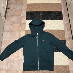 Mörkgrön Levis hoddie. Storlek S - Avklippta snören gör den mer stilren, annars inga anmärkningar.