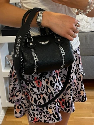 Mönstrad volangkjol - Superfin kort kjol med leopardmönster med bred smock i midjan och dubbla volanger i lila toner. Passar XXS. 