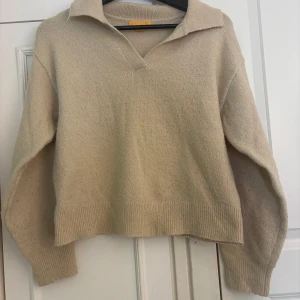 Beige stickad tröja med krage - Beige stickad tröja med v-ringning. Perfekt för lager-på-lager och chill vibes. Tröjan är lite knottrig men annars i bra skick!