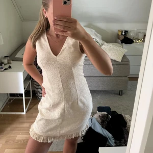 Vit kort ärmlös klänning med frans - Superfin vit kort klänning med v-ringning och ärmlös design. Materialet är strukturerat och nederkanten har snygga fransdetaljer. Perfekt för dig som gillar stilrena och trendiga plagg. Från hm, aldrig använd! 