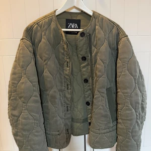 Quiltad jacka från Zara - Säljer en oversized mörkgrön quiltad jacka från Zara. Jackan har rund halsringning, knappar och dragkedja framtill samt två fickor. Är i storlek S