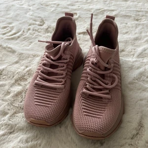 Rosa sneakers från Steve Madden - Snygga rosa sneakers från Steve Madden med stickad ovandel och coola detaljer. Skorna har snörning och en chunky sula i matchande ton. Perfekta för dig som gillar sportig och trendig stil. Lätta och bekväma med modern design.
