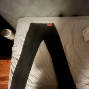 Levi's 501 svarta jeans W32 L32 - Svarta Levi's 501 jeans med klassisk rak passform och normal midja. Jeansen är tillverkade i slitstarkt bomullstyg och har den ikoniska läderpatchen bak i midjan. Perfekta för dig som gillar en tidlös och clean look. Skickar samma dag eller dagen där på