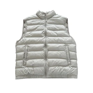 Ljusgrå dunväst från Zara - Snygg ljusgrå dunväst från Zara med quiltad design och hög krage. Västen har två sidofickor med dragkedja och stängs framtill med en hel dragkedja. Perfekt att slänga över en hoodie för extra värme under kyliga dagar.