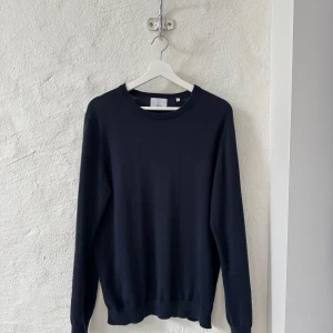 Stickad Tröja Bläck - Säljer en mörkblå stickad tröja från Bläck i storlek M, modell "MENTON KNITTED SWEATER". Tröjan är i nyskick och köptes i maj i år för 600 kr. Kvitto medföljer.