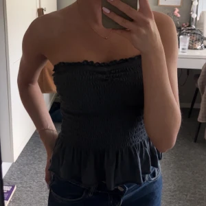 Mörkgrå bandeau tubtopp  - Supersöt bandeau tubtopp i mörkgrått med smockad struktur och volangkant nedtill. Toppen är från Zalando (Amercian Eagles) och är väldigt stechigt!💕