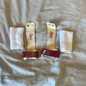 IWA Goldline Grip gymnastikhandskar M/3 - Säljer ett par IWA Goldline Grip gymnastikhandskar i storlek M/3. Handskarna är i ljust skinn med röda remmar och två hål för fingrarna. Medföljer två vita svettband i frotté. Perfekta för träning på räck eller barr.