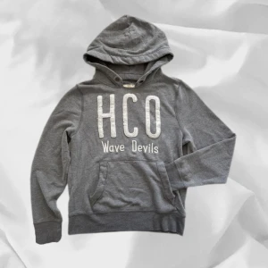 Hollistee Hoodie - Snygg hoodie från Hollister i grå – enkel att matcha och skön att bära. Ett stilrent val, noggrant utvalt med omsorg av AM Clothing.  📩 Frågor? Hör gärna av dig! 📲 Följ oss här på Plick för fler uppdateringar. ♻️ Tack för att du handlar mer hållbart med AM Clothing!